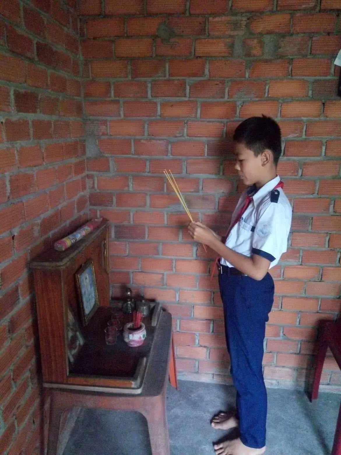 Nguyễn Minh Cảnh reading beside a brick wall