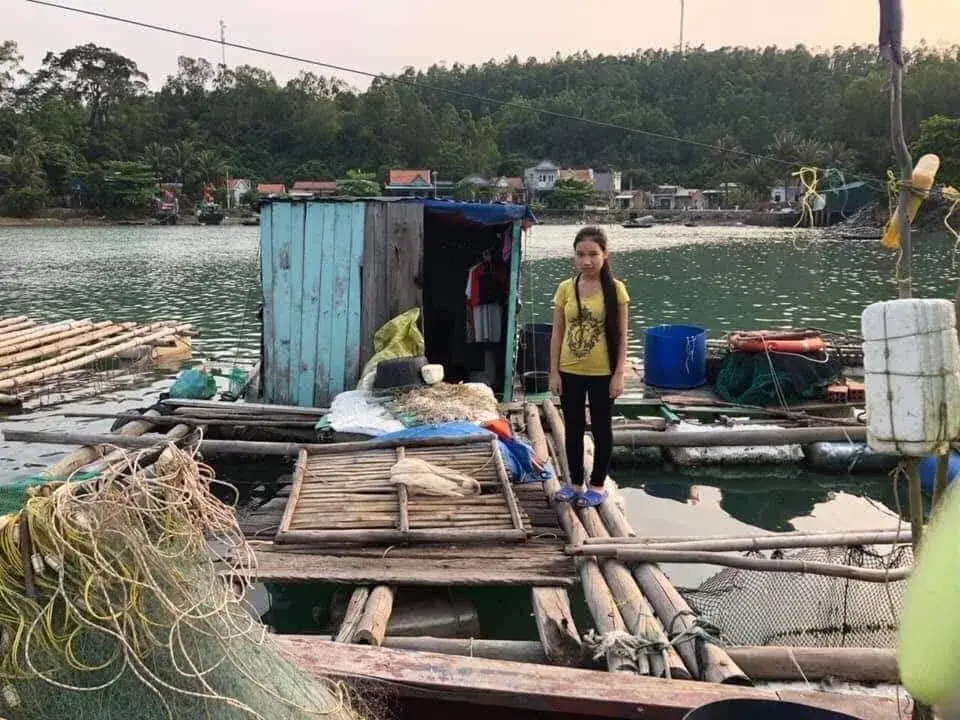 Nguyễn Thị Hậu standing beside her family’s fishing boat