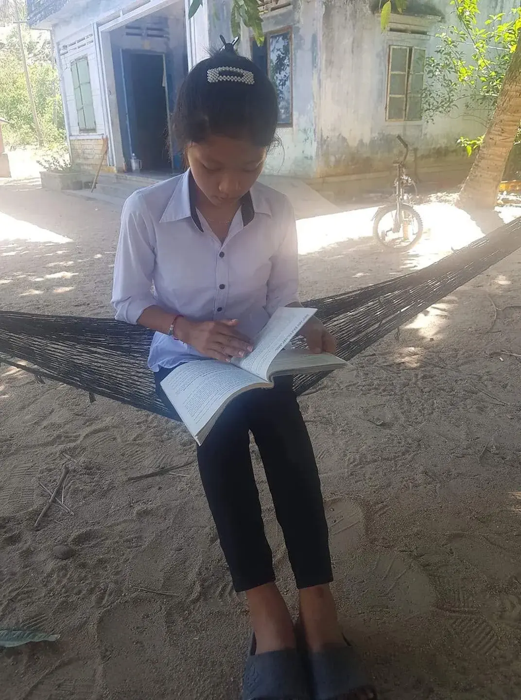 Nguyễn Thị Kim Hồng reading while resting in a hammock