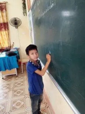Nguyễn Văn Sơn writing on a classroom chalkboard