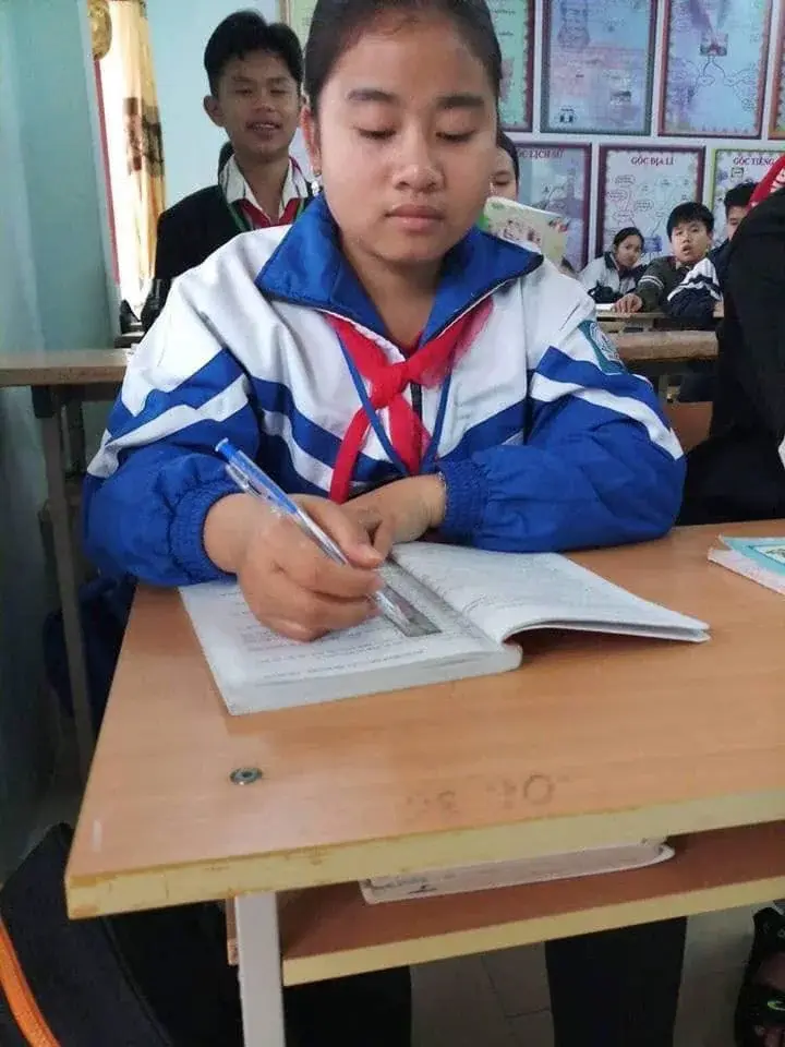 Quàng Quỳnh Giang writing carefully in a school notebook